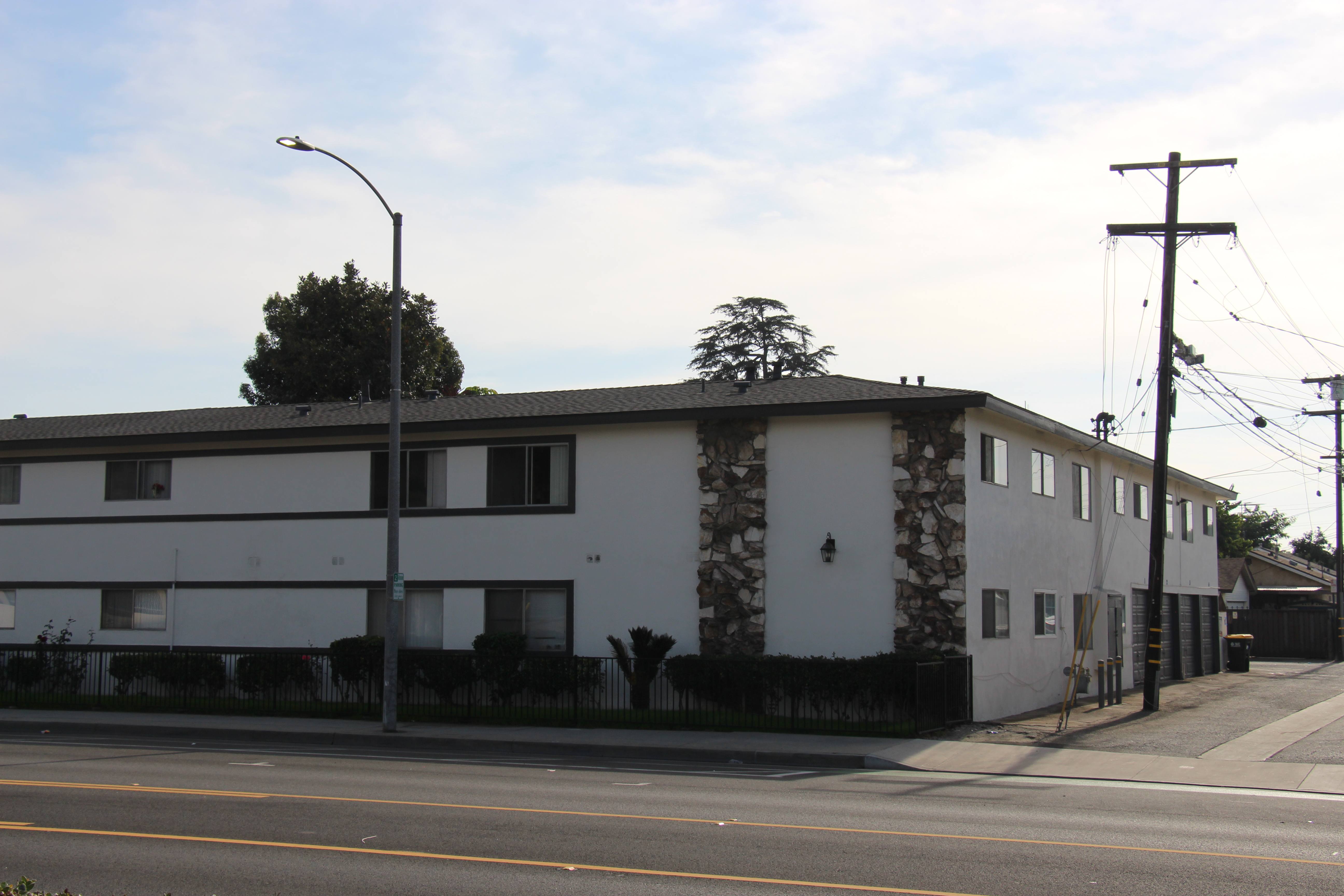 A white building with a black roof and a stone pillar on the side.